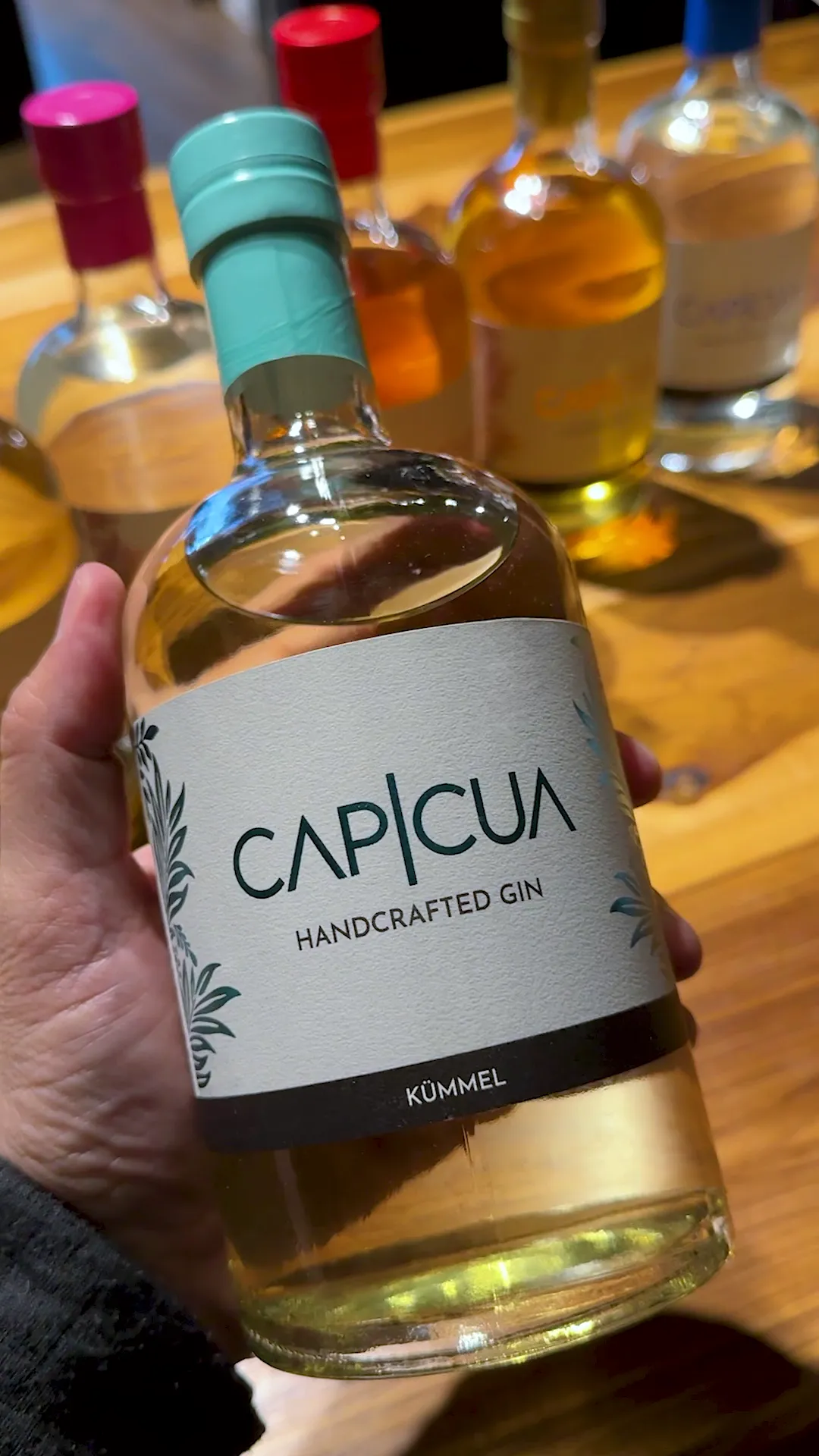 Botella de Kümmel CAPICÚA sostenida frente a la barra
